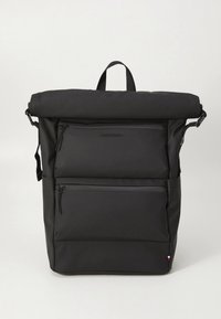 Sac à dos noir à rabat roulé en tissu durable. Comprend deux poches avant zippées et une poignée supérieure. Design minimaliste avec un logo et des accents.