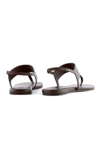 Sandali neri piatti con un design minimalista, dotati di una sola fascia e di un cinturino alla caviglia texturizzato, realizzati in materiale flessibile.