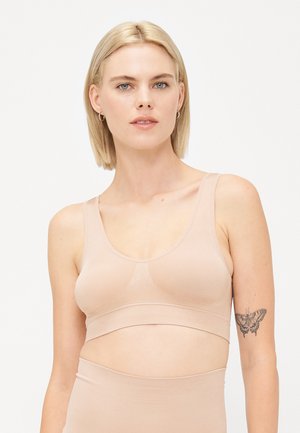 Lichtroze naadloze bralette met een ronde halslijn, brede banden en een textuurontwerp aan de voorkant. Zacht materiaal reikt tot halverwege de taille.