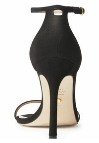Schwarze Wildleder-Sandaletten mit hohen Absätzen, einem Knöchelriemen, spitzer Zehenpartie und einem geschwungenen Rückendesign. Sie verfügen über einen zierlichen Stiletto-Absatz und eine leichte Innensohle.