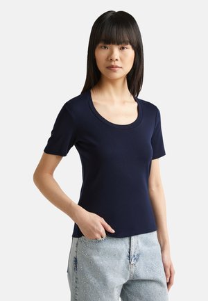Camiseta de manga corta azul marino hecha de una tela ligera, con escote redondo y un diseño ajustado, combinada con unos jeans de mezclilla claros.