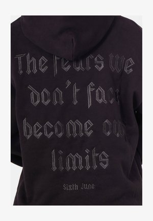 Zwarte hoodie met capuchon, met zilverkleurige gotische tekst op de achterkant: "De angsten die we niet onder ogen zien, worden onze grenzen. Sixth June." Zachte textuur.