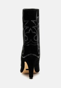 Botine negre din suede cu vârf ascuțit și toc stiletto de 10 cm. Prezintă detalii inspirate din stilul western, cu cuie argintii pe părțile laterale.