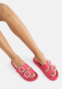 Infradito rosa con doppi accenti in gemma finta a forma di quadrato. Parte superiore testurizzata e suola imbottita per il comfort, design open-toe.