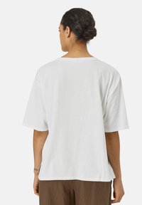 Witte t-shirt met korte mouwen van katoen, met een relaxte pasvorm en zijsplitten aan de onderkant voor meer bewegingsvrijheid. Eenvoudig ontwerp, geen patronen.