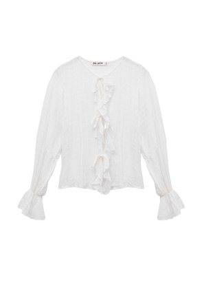 Blouse blanche à manches longues en tissu texturé, avec un détail froncé central et des manches évasées. Lien au niveau du col.