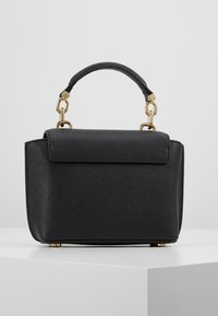 Kleine zwarte handtas van getextureerd materiaal, voorzien van een handvat aan de bovenkant, gouden accenten en een klepsluiting.