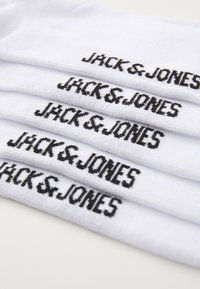 Chaussettes en coton blanches empilées, avec "JACK & JONES" brodé en noir sur chaque chaussette. Texture lisse avec un haut côtelé.