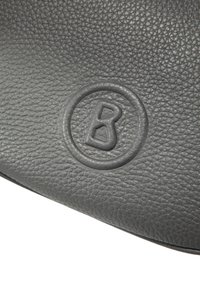 Šedá kožená kabelka s texturovaným povrchem. Obsahuje kulaté reliéfní logo se stylizovaným písmenem "B" uprostřed.