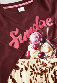 Maroon sweatshirt featuring a colorful ice cream sundae graphic with cherries and a beige bottom with brown leopard print accents.