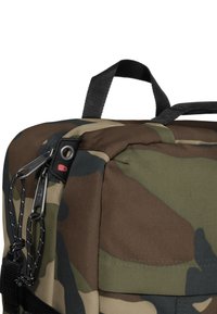 Mochila de camuflaje con tejido duradero en verde, marrón y beige, con herrajes negros y un tirador de cremallera doble para un cierre seguro.