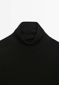 Zwart geribbeld stoffen coltrui met de kraag naar beneden gevouwen op een witte achtergrond.