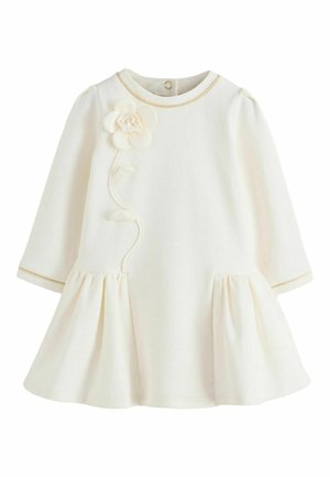 Robe bébé crème à manches longues avec jupe froncée, bordure dorée au col et aux poignets, et une application florale 3D avec une tige sur la poitrine.