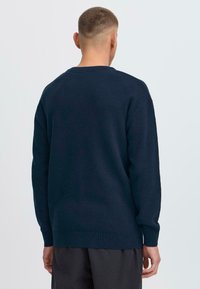 Sötétkék kötött pulóver hosszú ujjakkal és bordás mandzsettával. Alap crew neck fazon, textúrált felülettel és laza szabású.