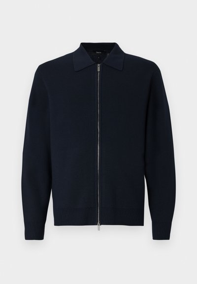 Cardigan tricotado azul-marinho com fecho em zíper, colarinho estruturado, punhos e bainha canelados. Textura suave com um design moderno e elegante.