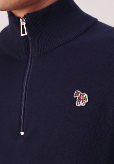 Tengerészszínű kötött pulóver magas gallérral, ezüst cipzárral és színes hímzett ló mintával a bal mellrészen.