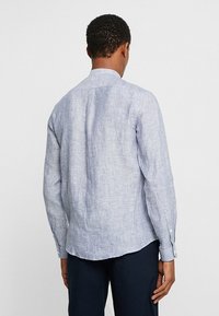 Camicia a maniche lunghe di colore azzurro chiaro con righe bianche, dotata di colletto classico, orlo sagomato e polsini con bottone. Tessuto morbido e traspirante.