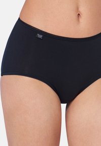 Zwarte onderbroek met een gladde textuur, hoge taille en een gekartelde rand. Voorzien van een klein logo-label op de tailleband.