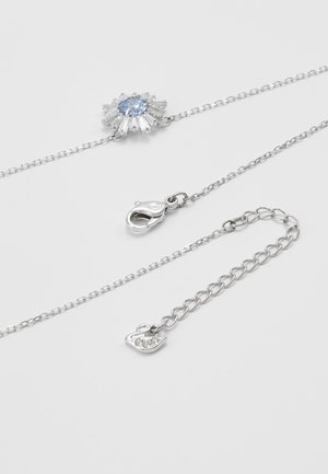 Collier chaîne en argent avec une pierre précieuse ovale bleue entourée de cristaux baguette clairs, fermoir mousqueton et extension ajustable en forme de cœur.
