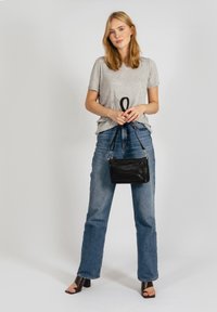 T-shirt gris à manches courtes, coupe décontractée, associé à un jean taille haute bleu. Sac à main en cuir noir avec bandoulière réglable et fermeture éclair.