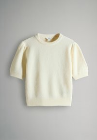 Kremowy sweter z krótkim rękawem z bufkami na ramionach, z prążkowanym okrągłym dekoltem, mankietami i dolnym wykończeniem, rozłożony na płasko na szarym tle.