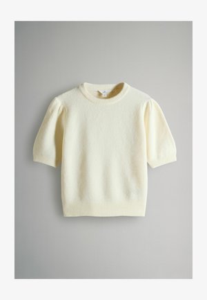 Krémový krátký svetr s nafouklými rameny, žebrovaným kulatým výstřihem, manžetami a lemem, položený na šedém povrchu.