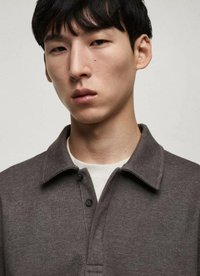 Gray polo shirt with a button-up collar, subtle texture, and visible stitching details. Worn over a light-colored inner layer.