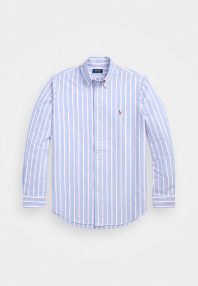Ανοιχτό μπλε πουκάμισο με κάθετους ροζ λωρίδες, γιακά, μακριά μανίκια και ένα μικρό κεντημένο λογότυπο στο στήθος. Κατασκευασμένο από βαμβακερό ύφασμα.