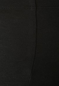 Tissu de legging noir avec une texture lisse et extensible. Comprend une couture verticale et un léger côtelé, adapté pour une tenue décontractée ou sportive.