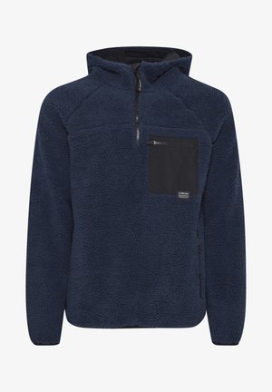 Mornarsko flis pulover s četrtinskim zadrgo, teksturirano površino, črn žep na prsih in kontrastnimi črnimi detajli na zadrgi ter žepu.