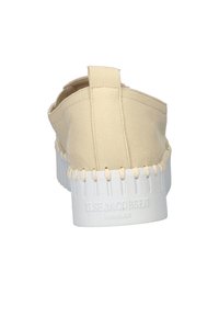 Beige instap-schoen met een textuur bovenkant en een witte rubberen zool. Heeft een gestikte tussenzool en een klein achterlipje voor gemakkelijk aan- en uittrekken.