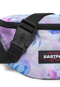 Lila blommönstrad tygmidjeväska med svart rem och spänne. Har en märkesetikett i svart med röd logotyp och dragkedja.