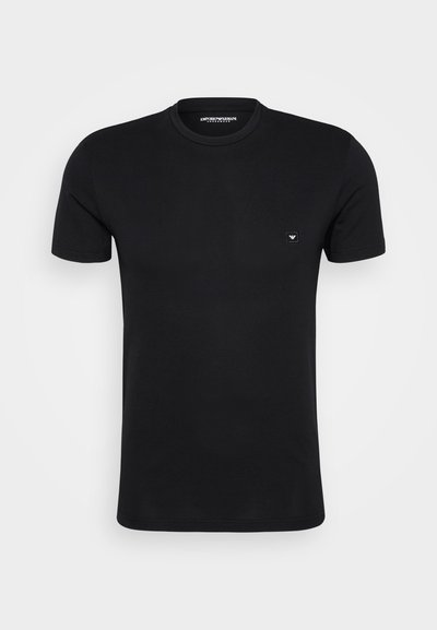 Juodas medvilnės marškinėliai trumpomis rankovėmis ir apvaliu iškirpimu. Yra mažas logotipo pleistras kairėje krūtinės pusėje. Lygus paviršius, minimalistinis dizainas.