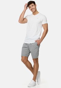 Hvid V-hals t-shirt, grå shorts med sidelommer og hvide sneakers. Casual outfit med et enkelt design og neutrale farver.