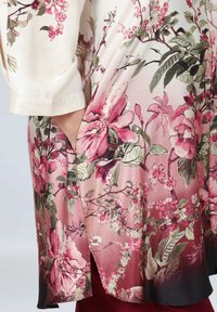 Floral kimono with short sleeves, featuring pink and green flowers on a creamy background. Fabric is smooth with a gradual darkening hem.