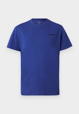 T-shirt in cotone blu royal con collo rotondo, maniche corte e un piccolo logo nero sul petto. Tessuto liscio, vestibilità casual.