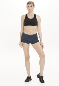 Svart sportbh med meshdetaljer, kombinerad med navy marmorerade shorts. Atletiska skor fulländar träningslooket. Minimalistisk design, funktionell passform.