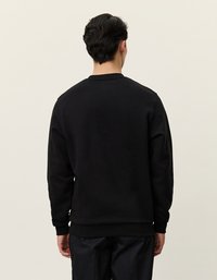 Svart hettegenser med rund hals, ribbet mansjett og hem. Enkel design uten synlige logoer eller mønstre, laget av myk, teksturert stoff.