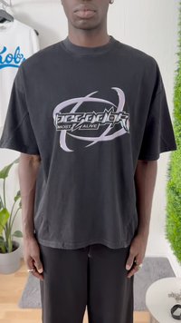 T-shirt oversized preto com mangas curtas. Apresenta um grande design gráfico metálico no centro que diz "mais vivo". Textura suave.