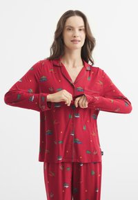 Conjunto de pijama rojo con mangas largas y pantalones, que presenta un estampado completo de coches y árboles. Está hecho de una tela suave y elástica con botones.