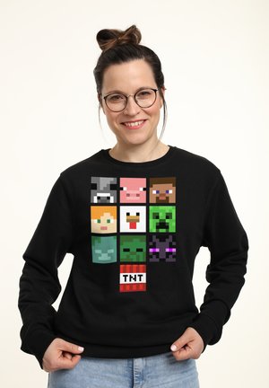 Czarna bluza z pixel artami postaci w siatce 3x3, z czerwoną kostką TNT na dole. Materiał bawełniany, fason z okrągłym dekoltem.