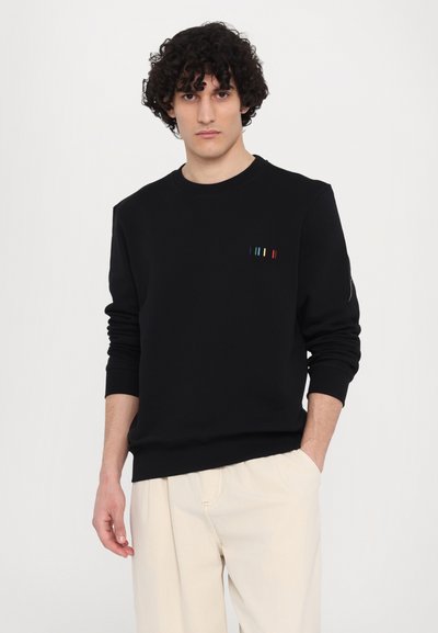 Sort sweatshirt med lange ærmer og rund halsudskæring, der har et flerfarvet stribet design på brystet. Glat stof, afslappet pasform.