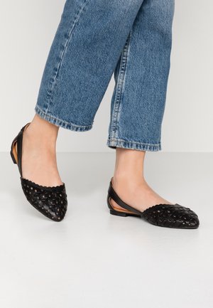 Sorte læder slingback-flats med flettet design, spids tå og bølgekantede kanter. Sålen er flad, egnet til afslappet brug.