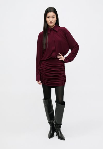 Bordo spalvos palaidinė su apykakle, derinama su ruošiniu sijonu, juodomis pėdkelnėmis ir aukštais juodos odos batais. Lygi tekstūra, prigludęs dizainas.