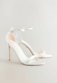 Sandali alti bianchi realizzati in morbido satin, con design open toe, sottili cinghie alla caviglia e tacco a stiletto.