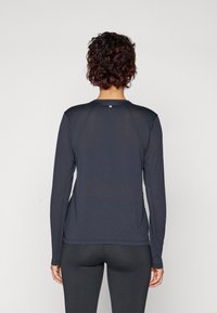 Langärmliges Sportshirt in Marineblau, aus leichtem Material gefertigt, mit Rundhalsausschnitt und dezentem Logo-Detail auf der Rückseite.