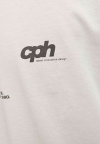 Valge puuvillane T-särk, mille esipinnal on suur must "cph" logo ja tekst "uusim uuenduslik disain". Sujuv tekstuur, pehme disain.