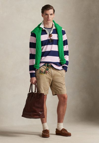 Triibuline pika varrukaga särk tumesinises ja roosas, roheline kaablimustriline vest, beež tikandiga lühikesed püksid, pruun nahast käekott ja paadisussid.