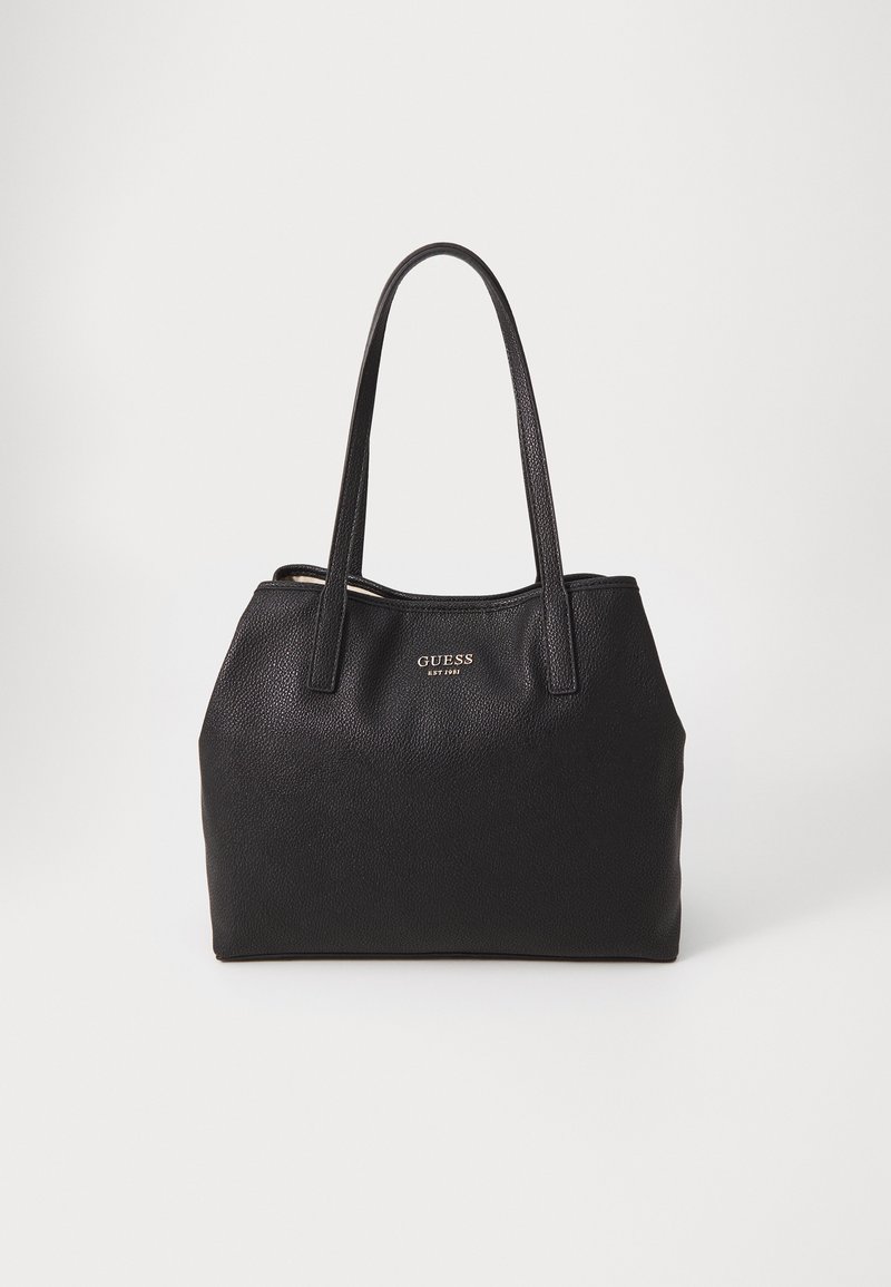 Grand sac fourre-tout en cuir noir grainé avec deux poignées robustes, présente le logo doré "GUESS" à l'avant, de forme rectangulaire et avec un intérieur lisse.