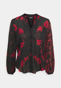 Czarna bluzka z guzikami, z czerwonym wzorem tie-dye, kołnierzykiem mandarin i długimi, bufiastymi rękawami z kwiatowymi wzorami na jednym z rękawów.